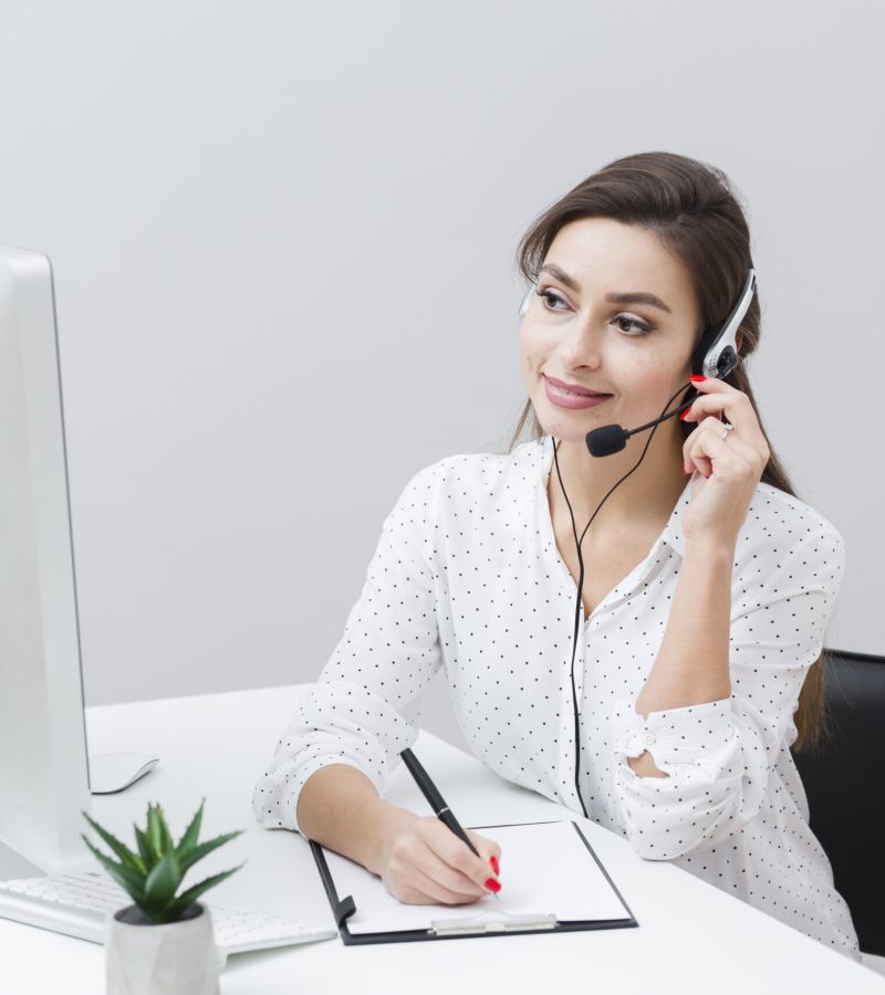 front-view-smiley-woman-writing-something-down-while-talking-headset front-view-smiley-woman-writing-something-down-while-talking-headset